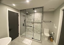 Modern bathroom with glass-enclosed shower, white toilet, and marble tile flooring